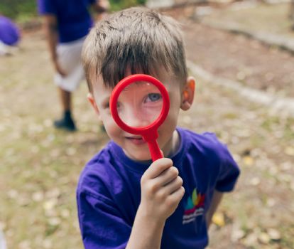 Child looking at camera with magnifying glass